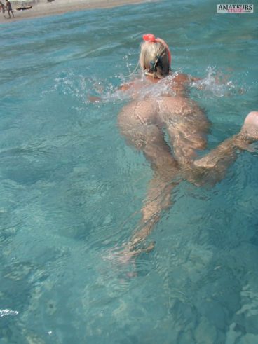 Nude swimming wife with her beautiful big butt just under the water surface at the beach