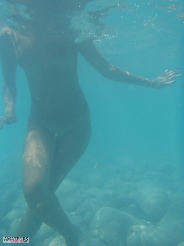 Naked wife standing with her legs crossed on the sea bottom