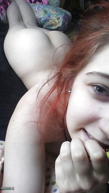 Naked redhead teen showing her tight ass in selfie while lying on bed